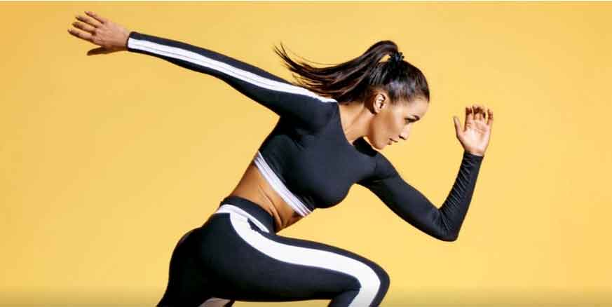 Sportlerin in dynamischer Sprintpose vor neutralem Hintergrund – Symbolbild für Kraft, Ausdauer und Motivation im Training.