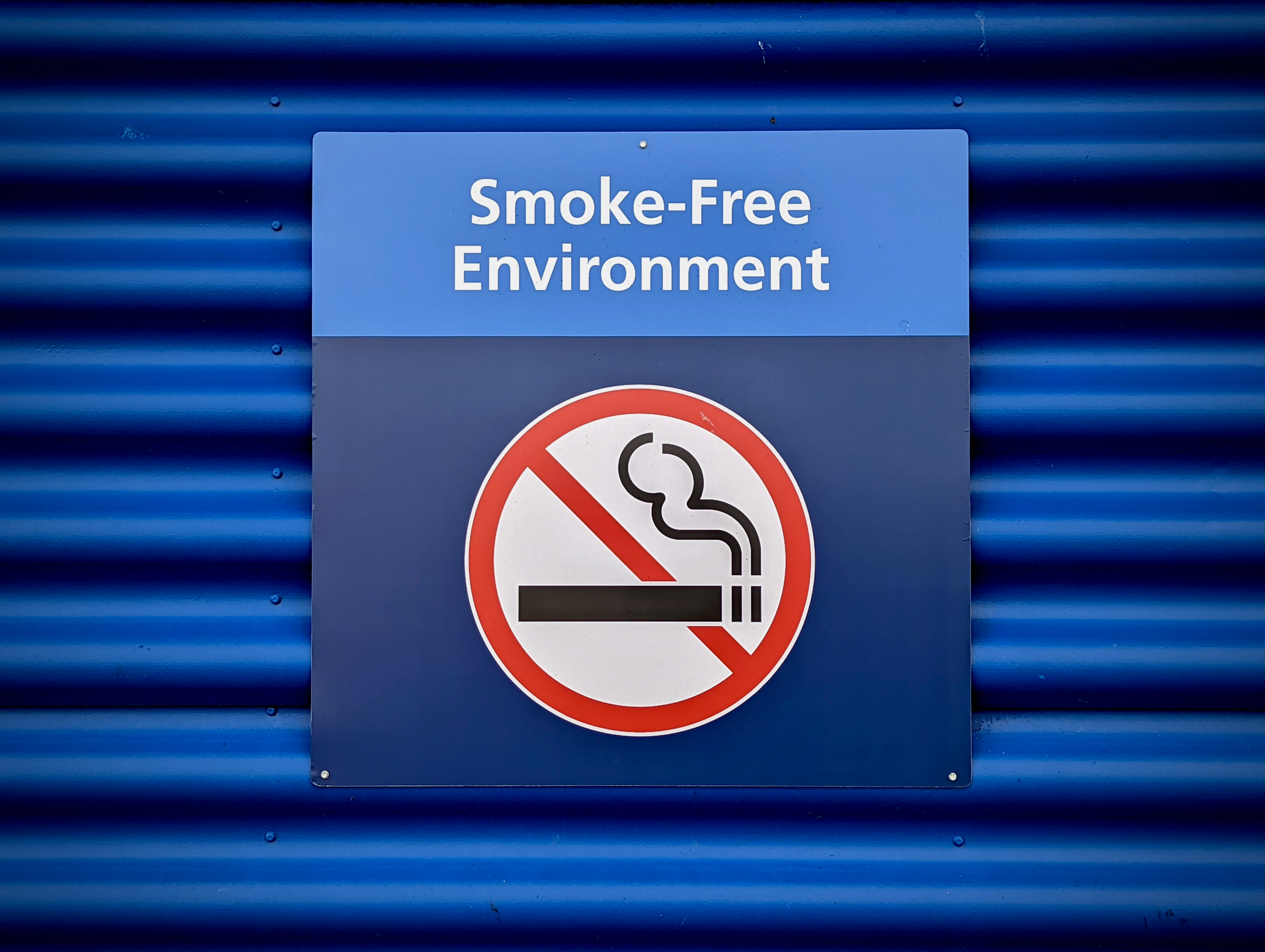 Rauchfrei sein Hinweisschild mit durchgestrichener Zigarette und Text „Smoke-Free Environment“ – Rauchen verboten.