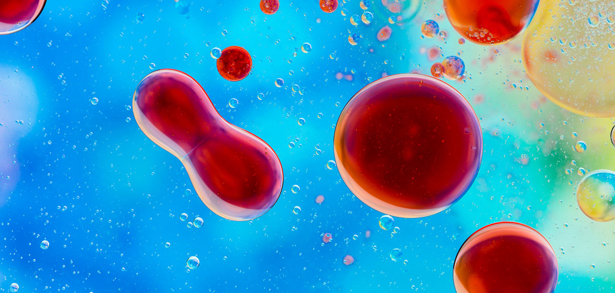 Immunsystem stärken Bunte Flüssigkeitstropfen in Blau, Rot und Orange unter dem Mikroskop, Darstellung von Zellen oder Molekülen in Nahaufnahme.