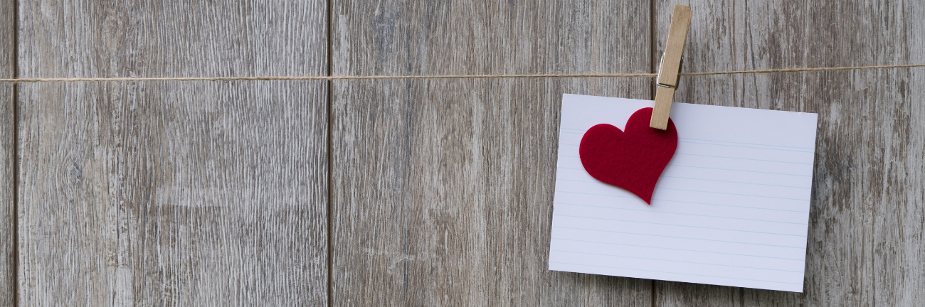 Eine Karte mit einem Herz, das an einer Wäscheleine mit einer Wäscheklammer befestigt ist.